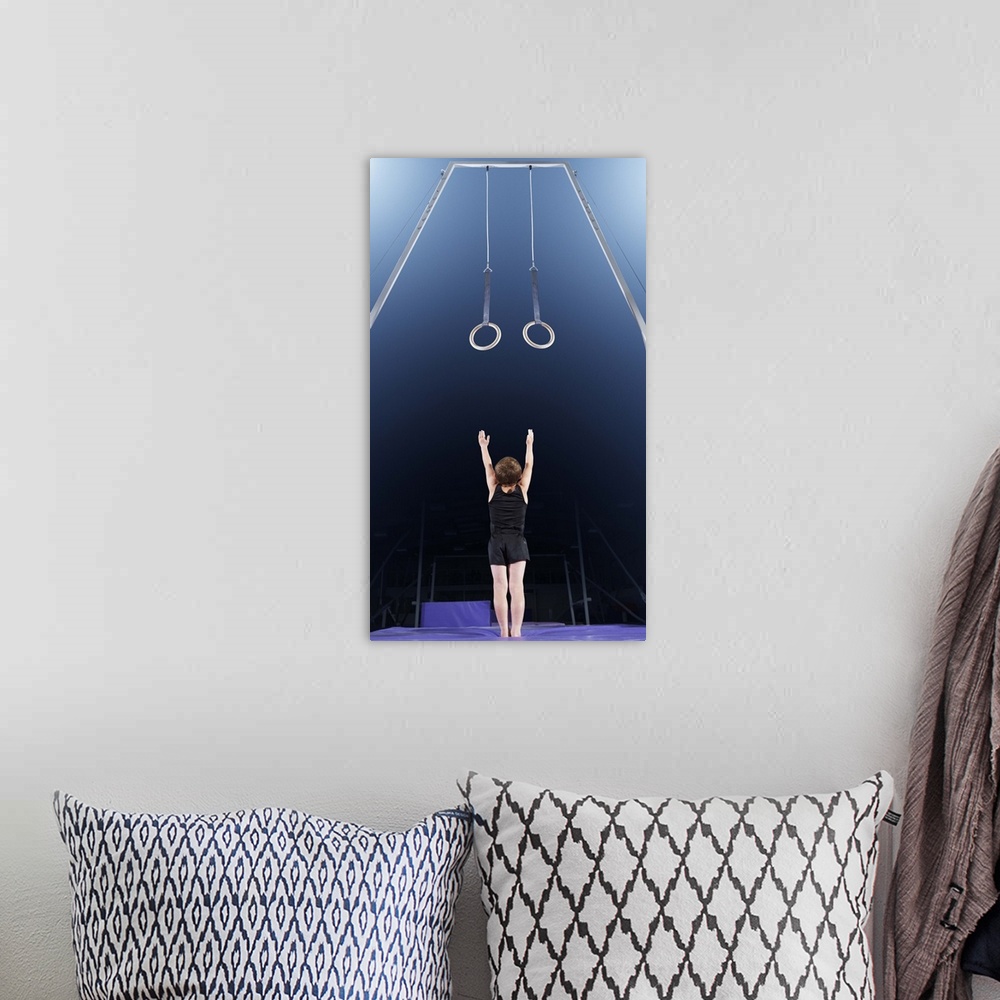 A bohemian room featuring Young male gymnast reaching up to rings
