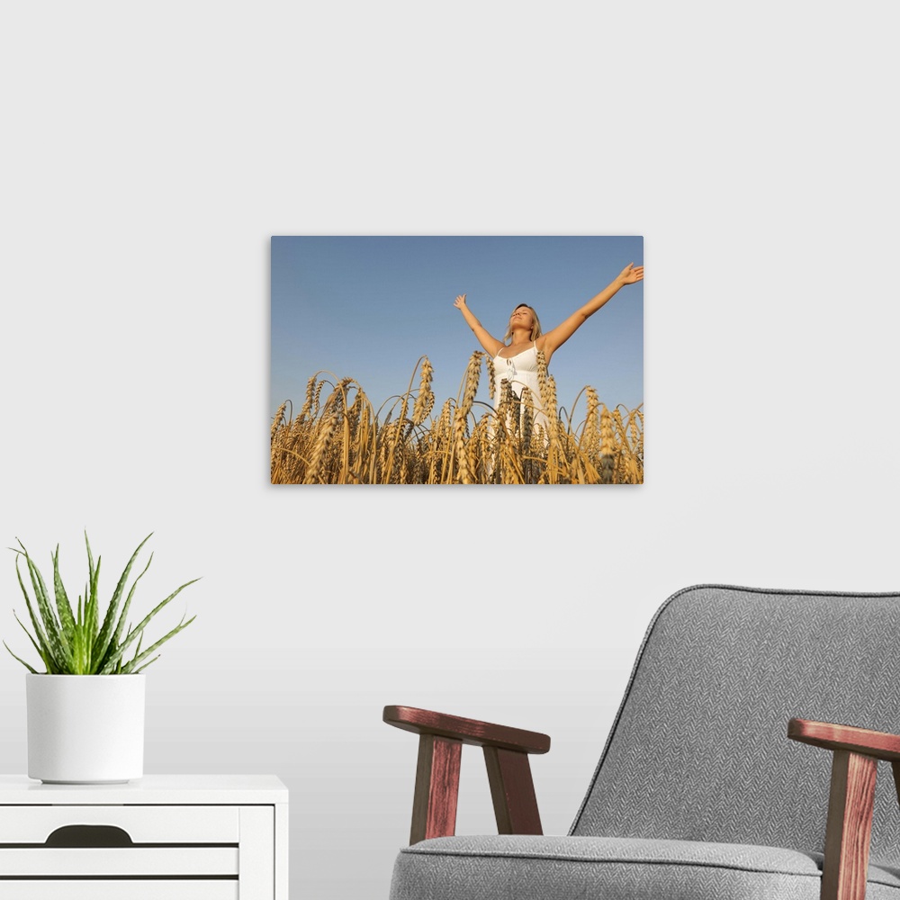 A modern room featuring Young woman in corn field with spread arms looking up.