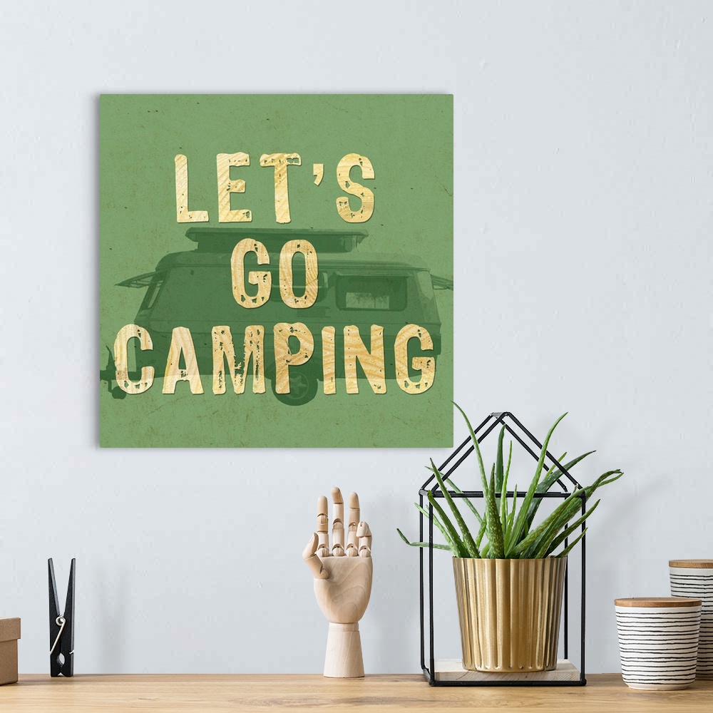 A bohemian room featuring A green-toned image of a recreational trailer with the words "Let's go camping."