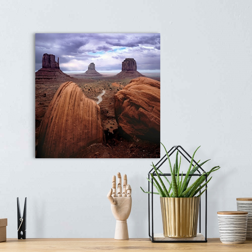 A bohemian room featuring A photograph of monument valley under a purple cloudy sky.