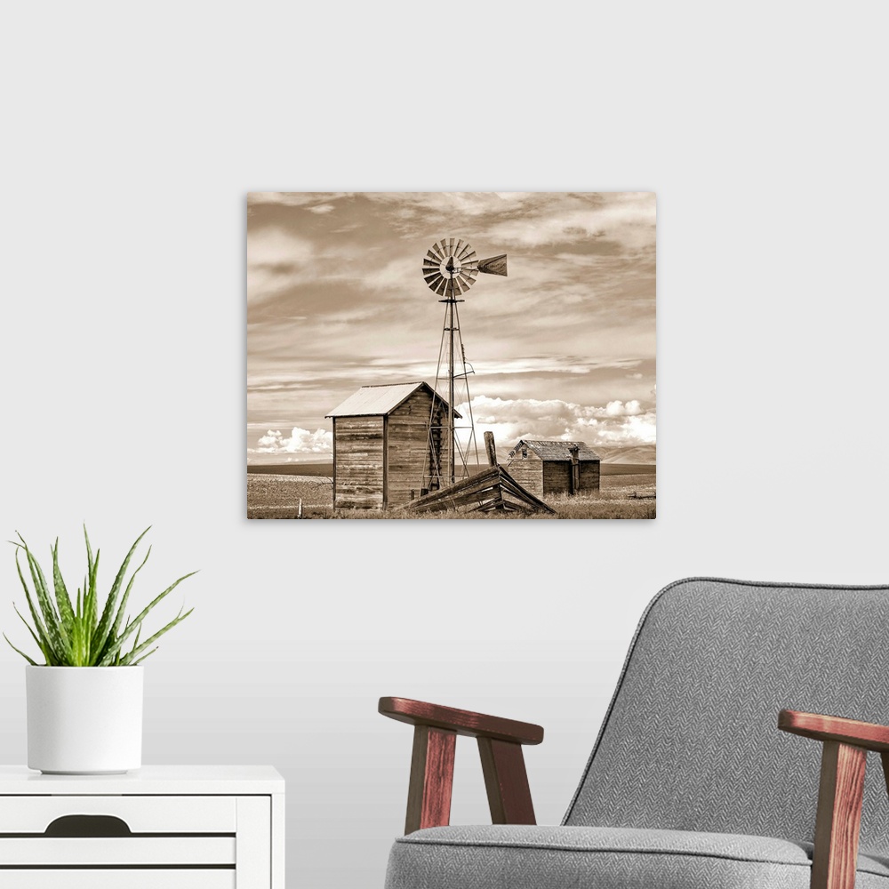 A modern room featuring A sepia photograph of a windmill and shed in a field with layers of clouds overhead.