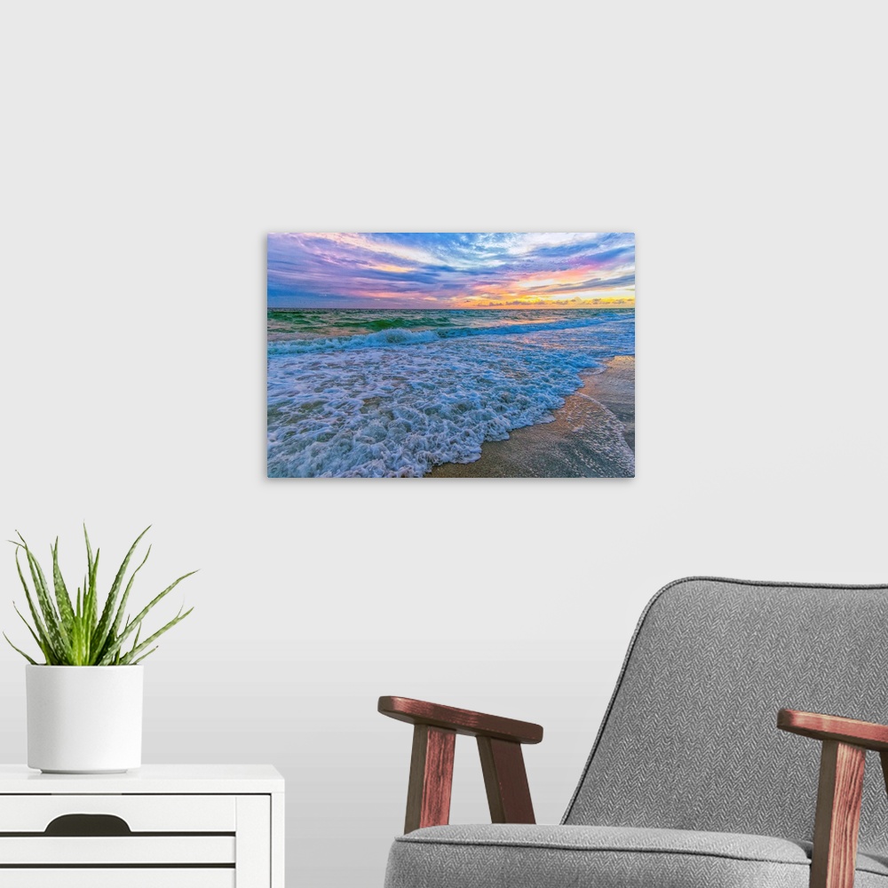 A modern room featuring A fine art photograph of a calm sea washing up onto a sandy beach. The sunrise provides an abunda...