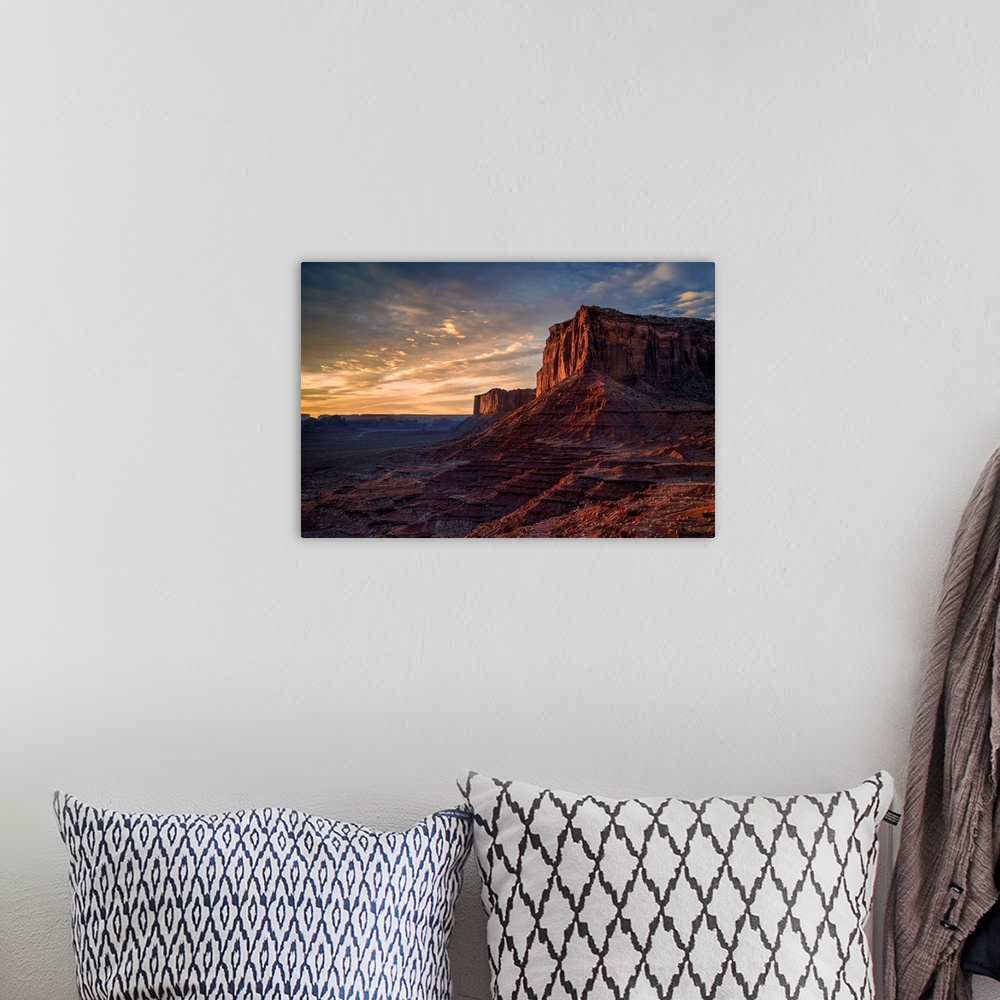 A bohemian room featuring The rising sun spreads warm light across the face of Monument Valley's Mitchell Mesa.