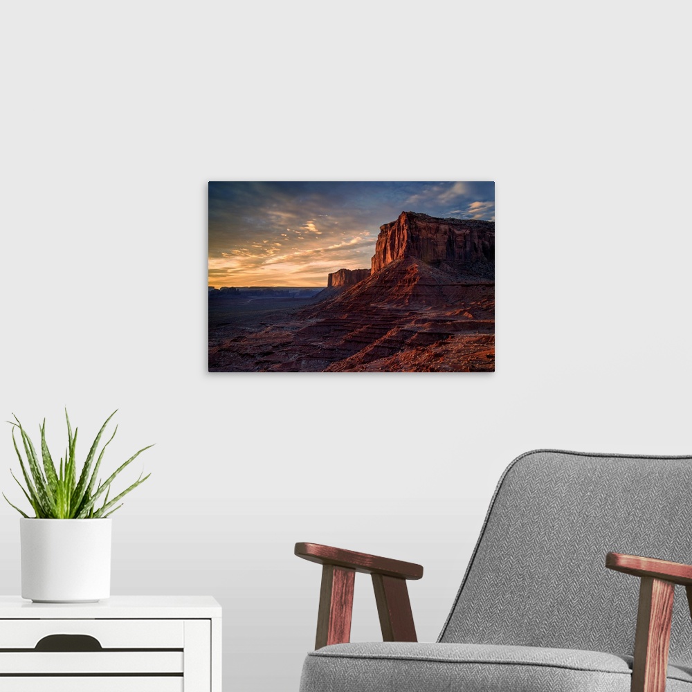 A modern room featuring The rising sun spreads warm light across the face of Monument Valley's Mitchell Mesa.