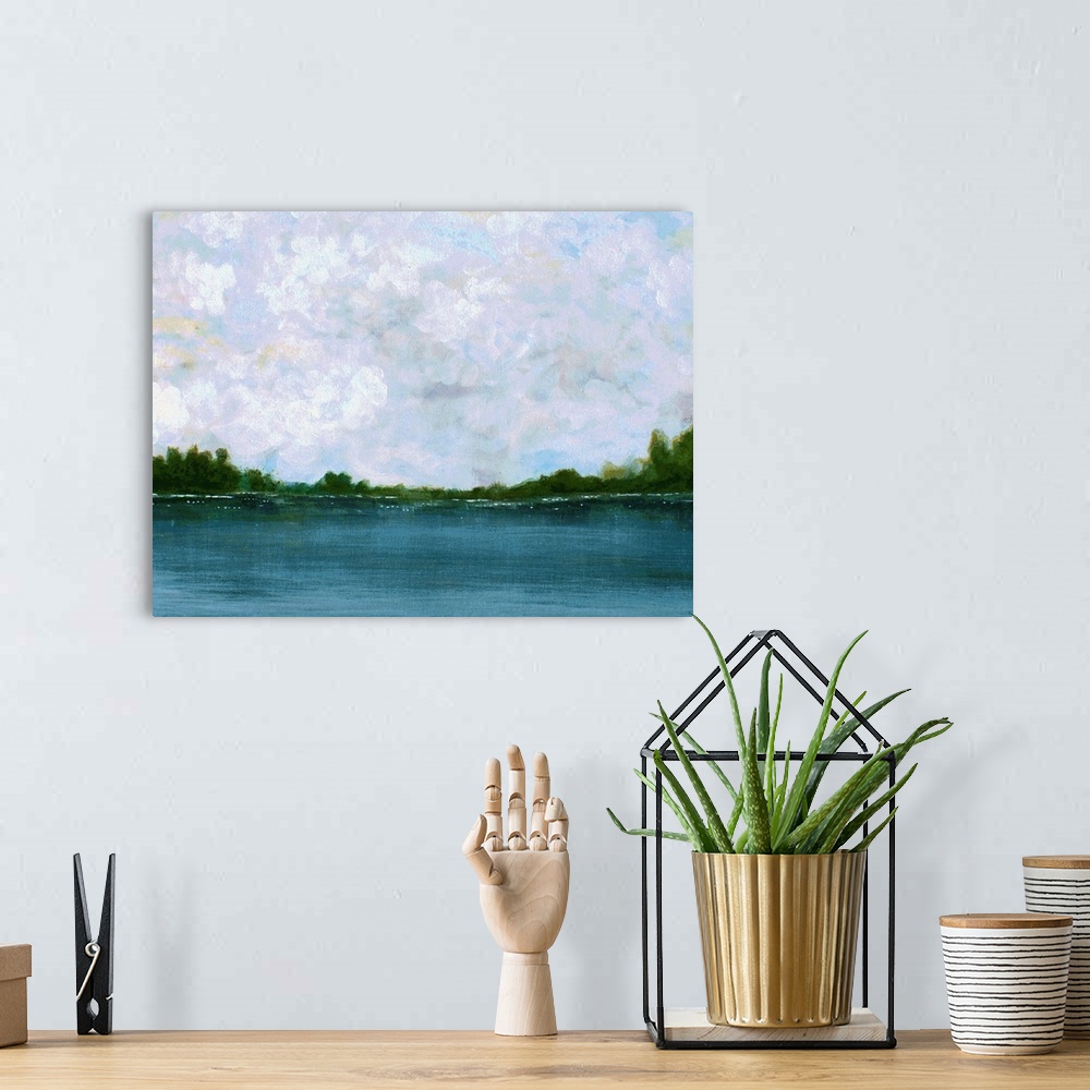 A bohemian room featuring Calm landscape painting with a peaceful lake lined with trees on the horizon and fluffy clouds in...