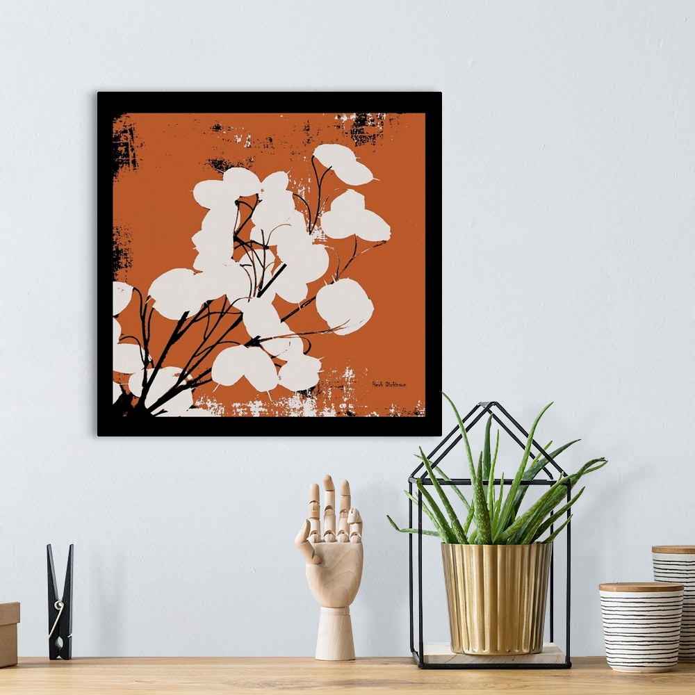 A bohemian room featuring Square silhouetted painting of a money plant in orange, black, and white with a black boarder.