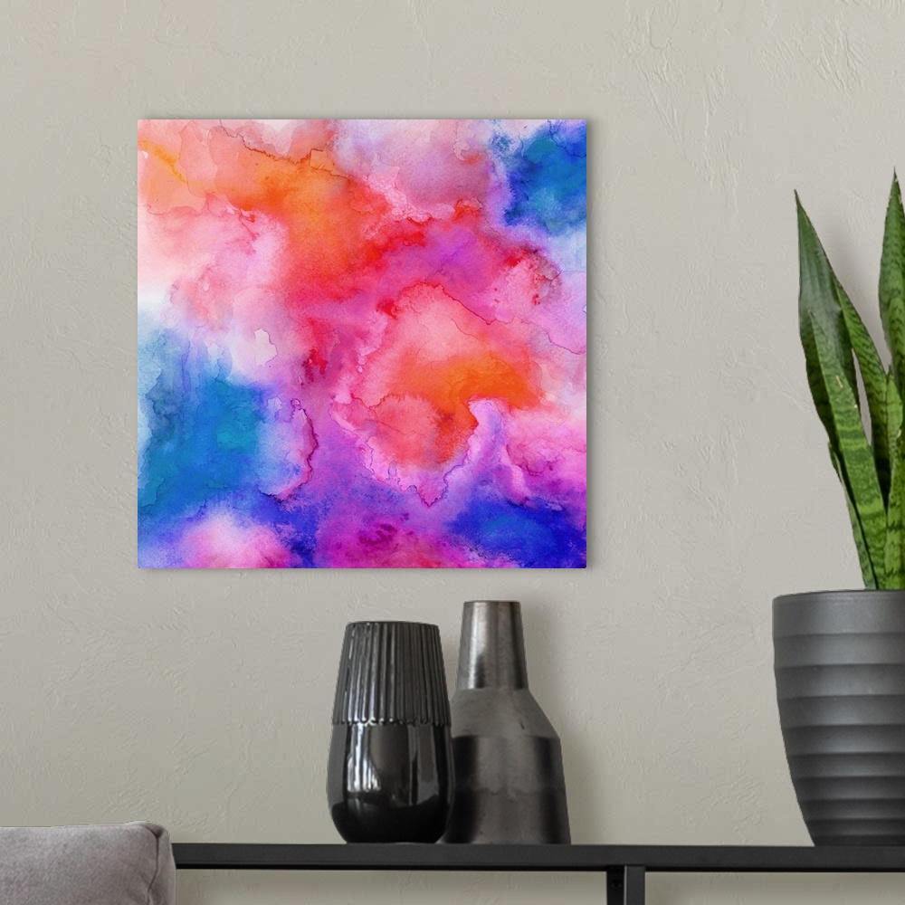 A modern room featuring A square abstract watercolor painting in brilliant colors of pink, orange and blue.