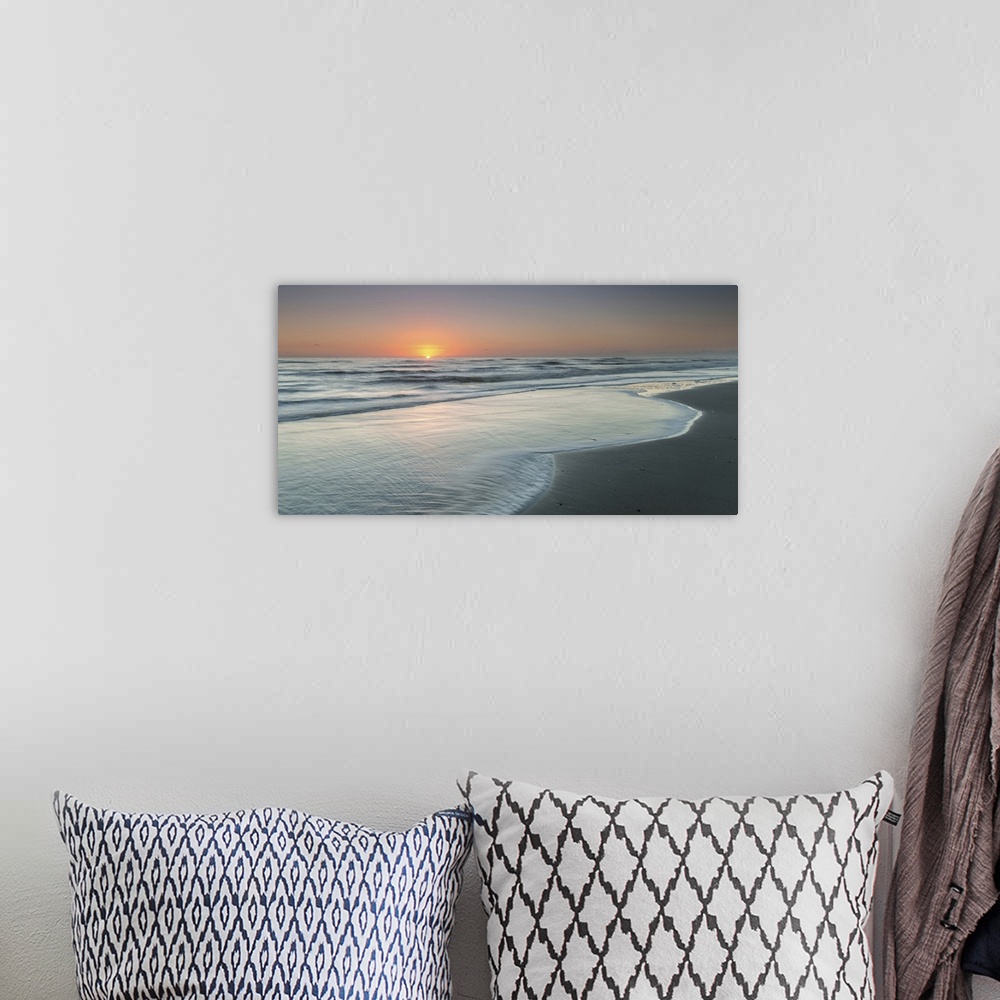 A bohemian room featuring A coastal photograph of a seascape at sunrise.