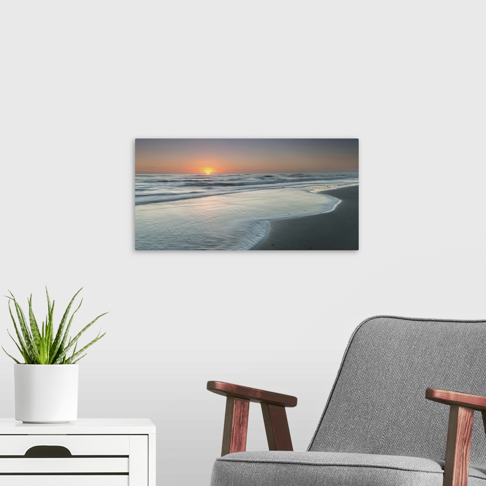 A modern room featuring A coastal photograph of a seascape at sunrise.