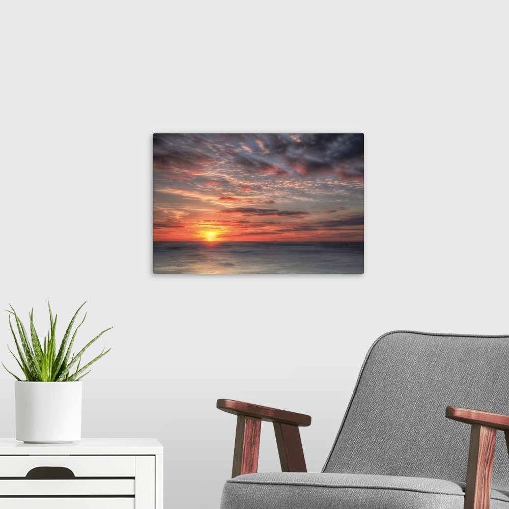 A modern room featuring A coastal photograph of a seascape at sunrise.