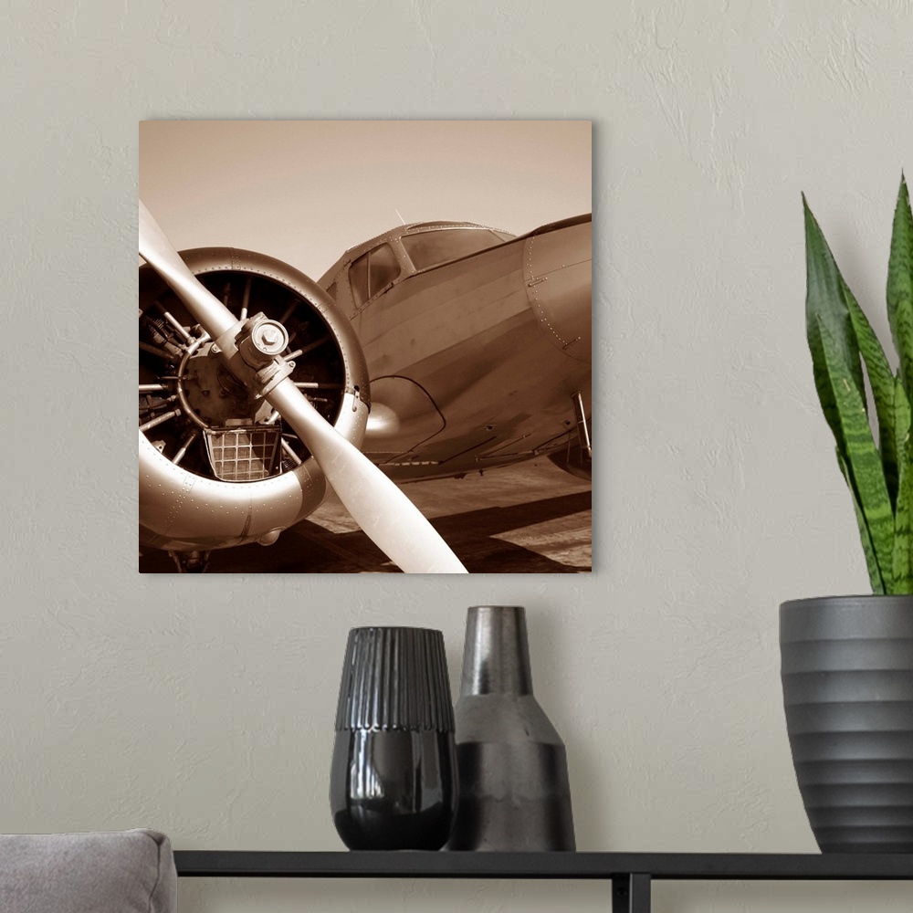 A modern room featuring Square photograph of a plane from the view of the wing in a sepia tone.