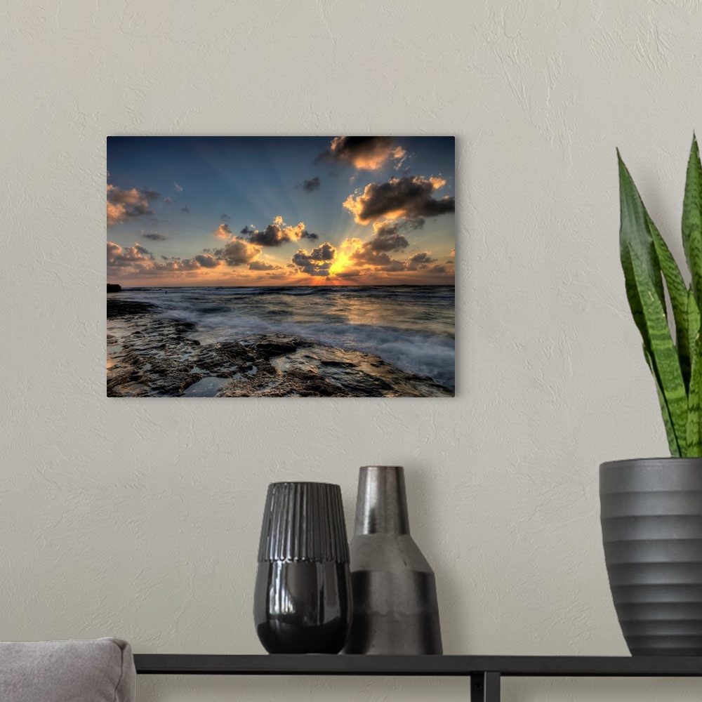A modern room featuring Horizontal photograph of a vibrant, golden sunset at a rocky beach.