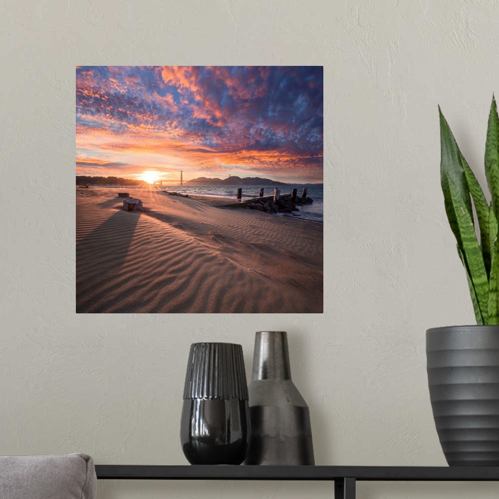 A modern room featuring A square photograph of a beach with the golden gate bridge in the background at sunset.