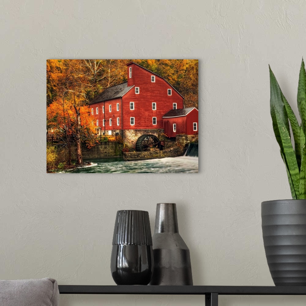 A modern room featuring A Photograph of an old rustic looking watermill. With rushing water in the foreground.