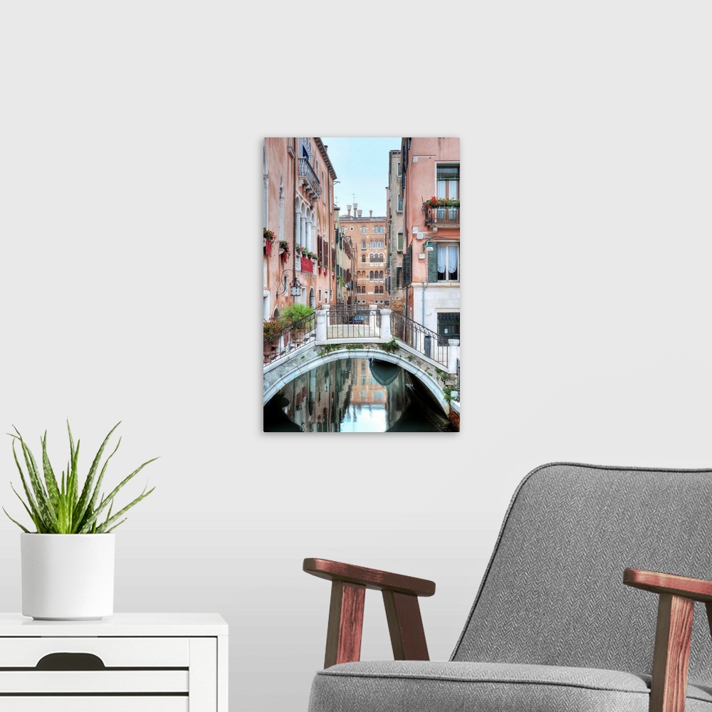 A modern room featuring A vertical scene of a walking bridge over a canal with the city reflecting in the water in Venice...