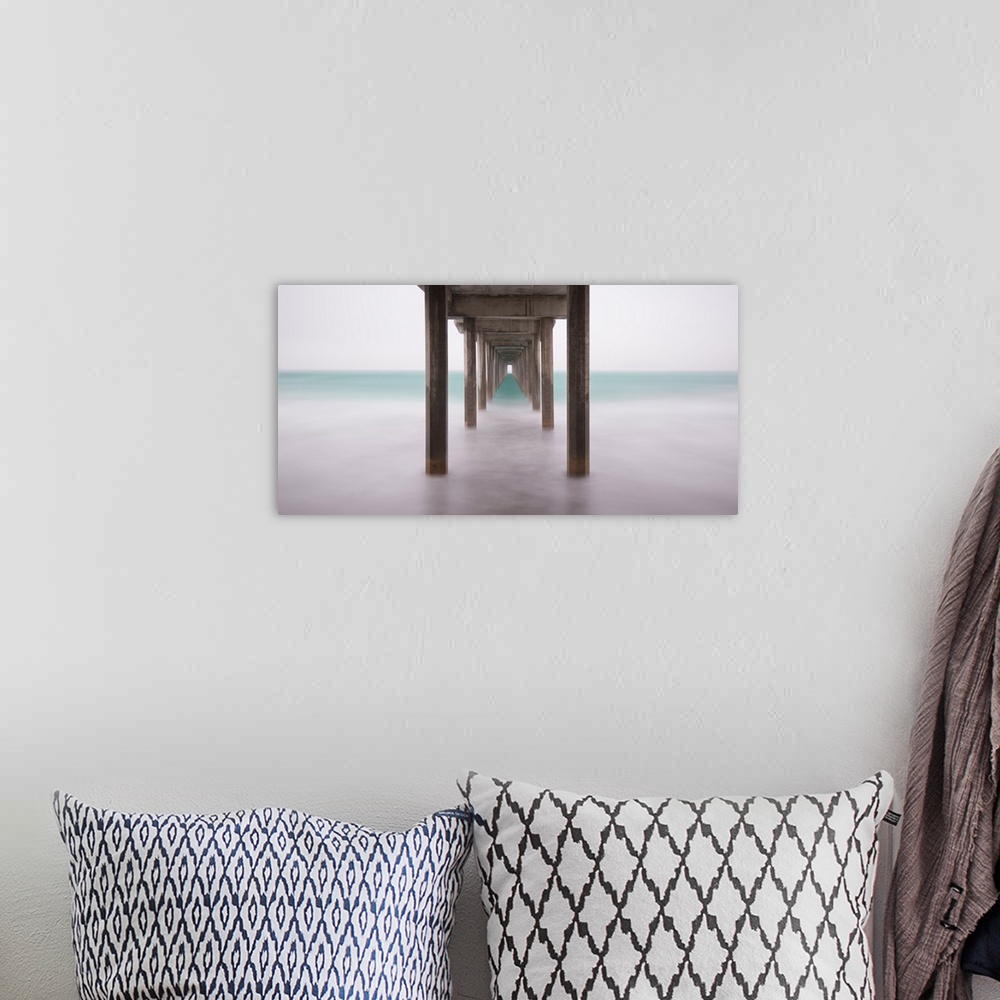 A bohemian room featuring A contemporary painting of the bottom side of a pier at a beach.