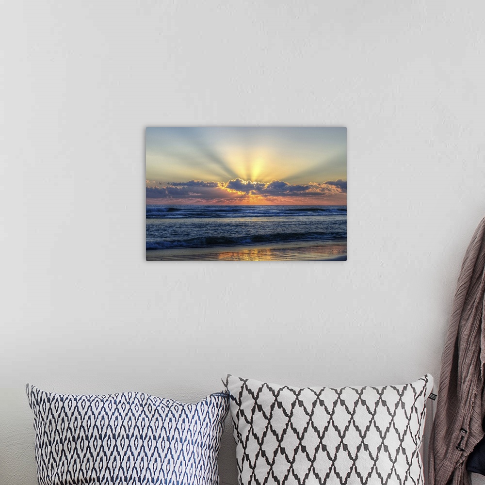 A bohemian room featuring A photograph of a vibrant sunrise behind textured clouds above a restless open sea.