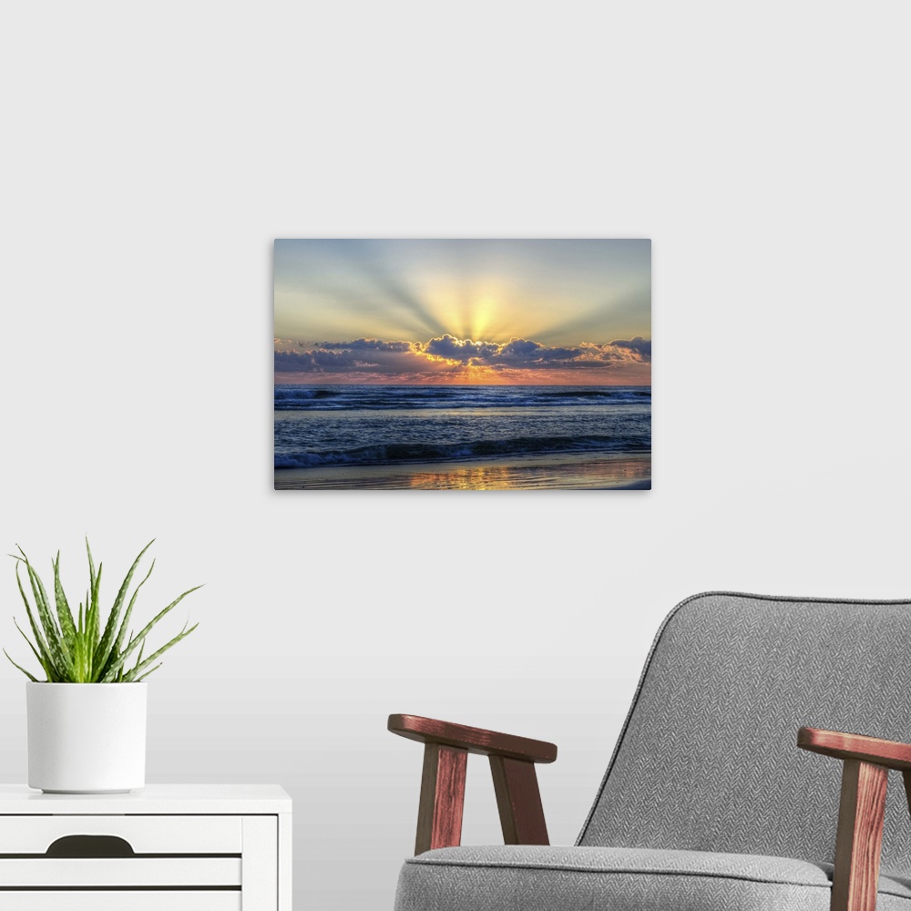 A modern room featuring A photograph of a vibrant sunrise behind textured clouds above a restless open sea.