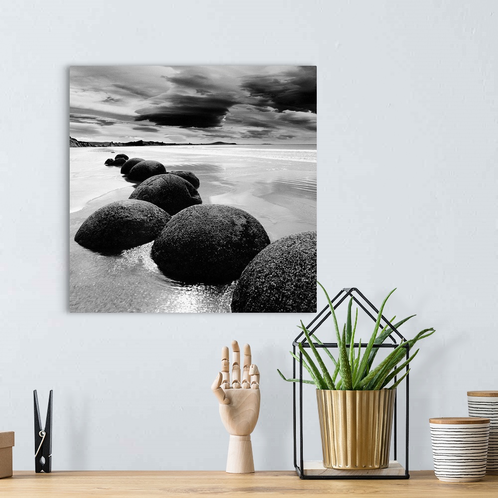 A bohemian room featuring Black and white photograph of a row of smooth rocks on a beach with a dramatic sky full of clouds.