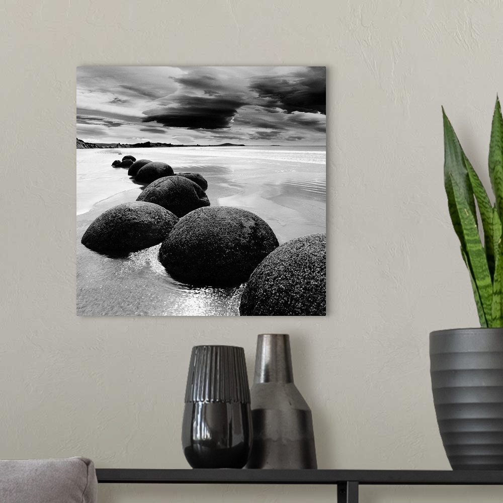 A modern room featuring Black and white photograph of a row of smooth rocks on a beach with a dramatic sky full of clouds.
