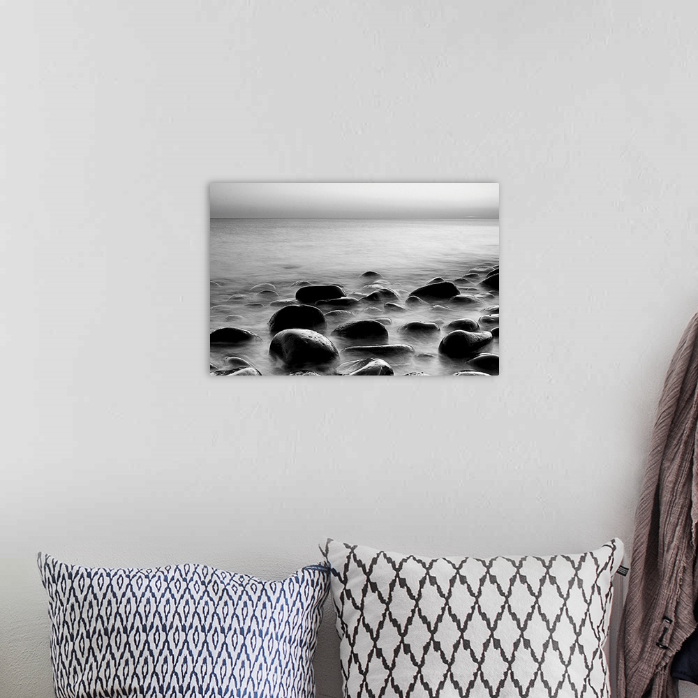 A bohemian room featuring Black and white photograph of layers of smooth rocks covered by water.