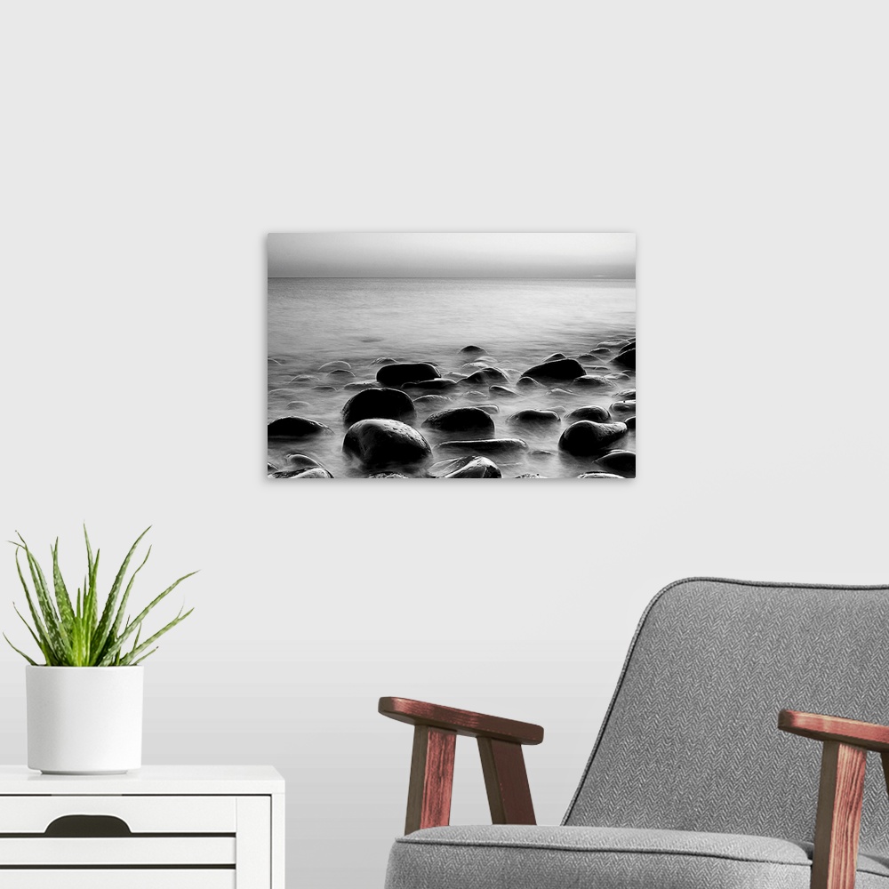 A modern room featuring Black and white photograph of layers of smooth rocks covered by water.