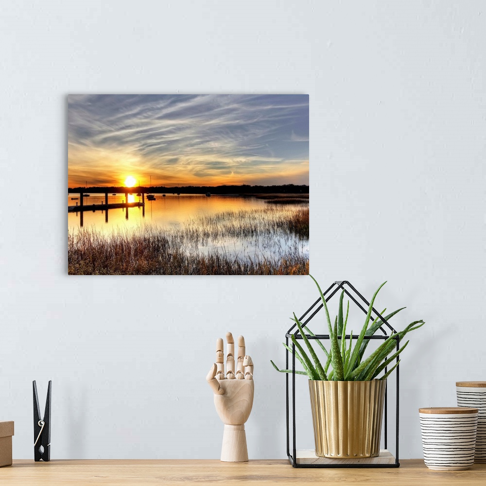 A bohemian room featuring A horizontal landscape of a sunset over a lake with boats on the water.