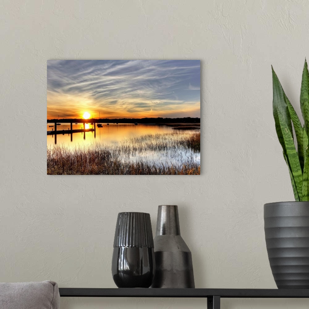 A modern room featuring A horizontal landscape of a sunset over a lake with boats on the water.