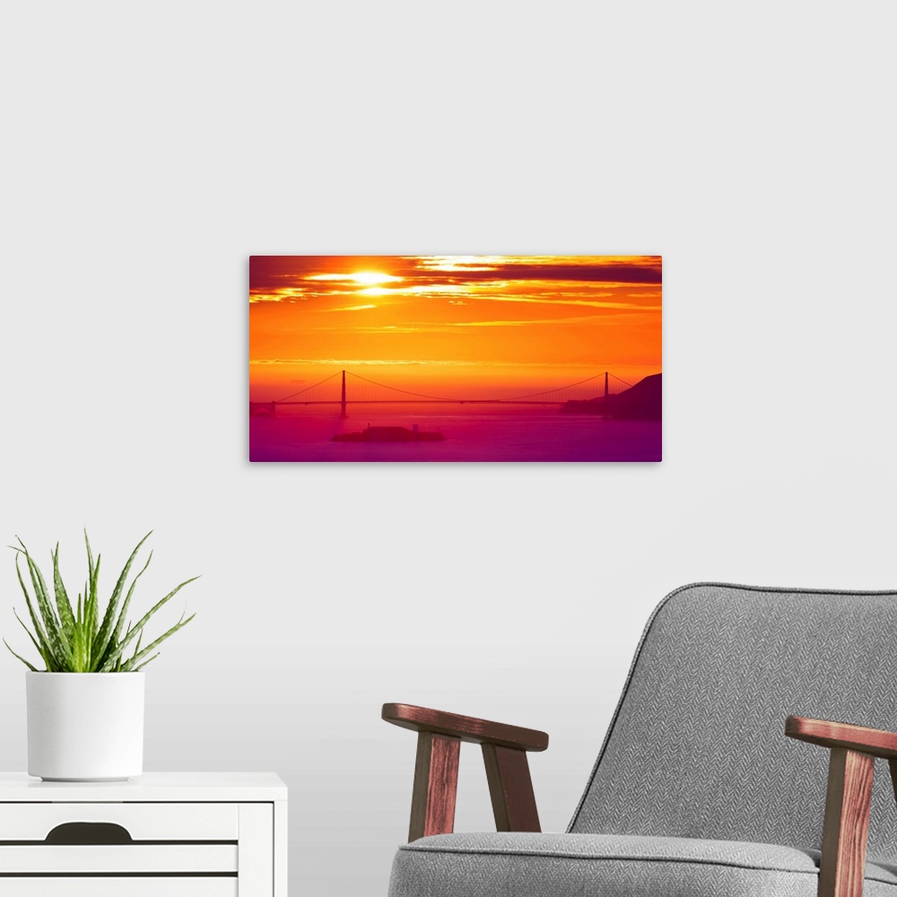 A modern room featuring A photograph of a vibrant sky at sunrise, with a bridge in hazy, misty morning light.