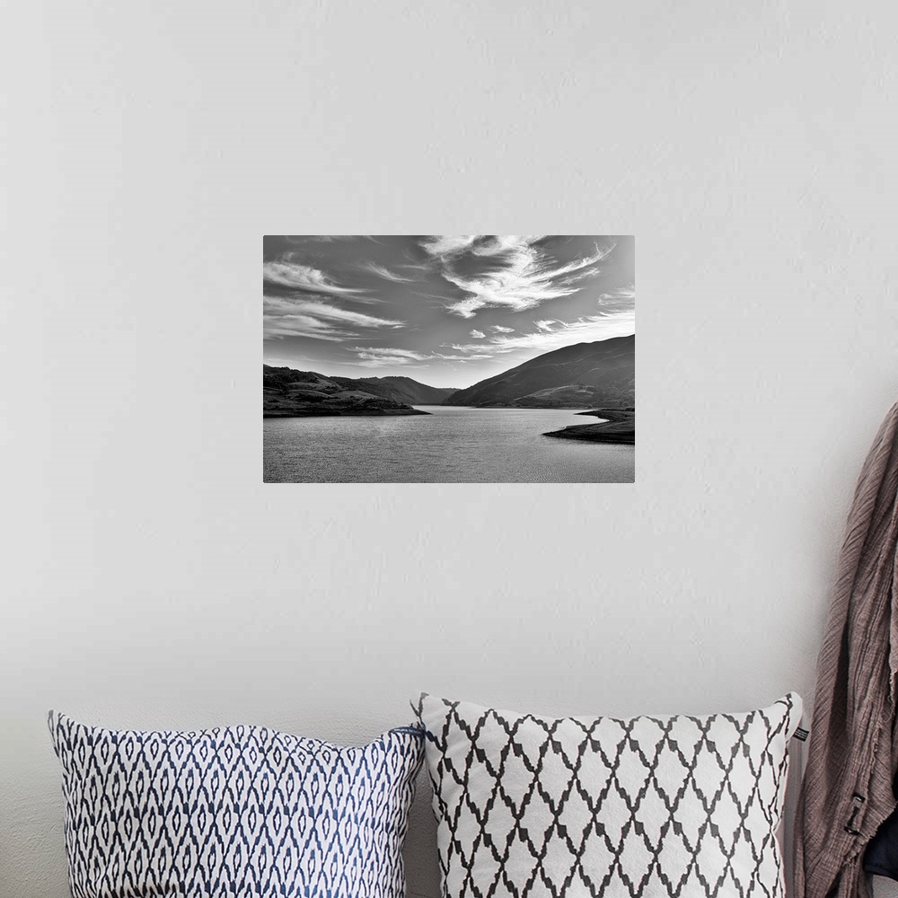 A bohemian room featuring A black and white landscape with a sky full of clouds.