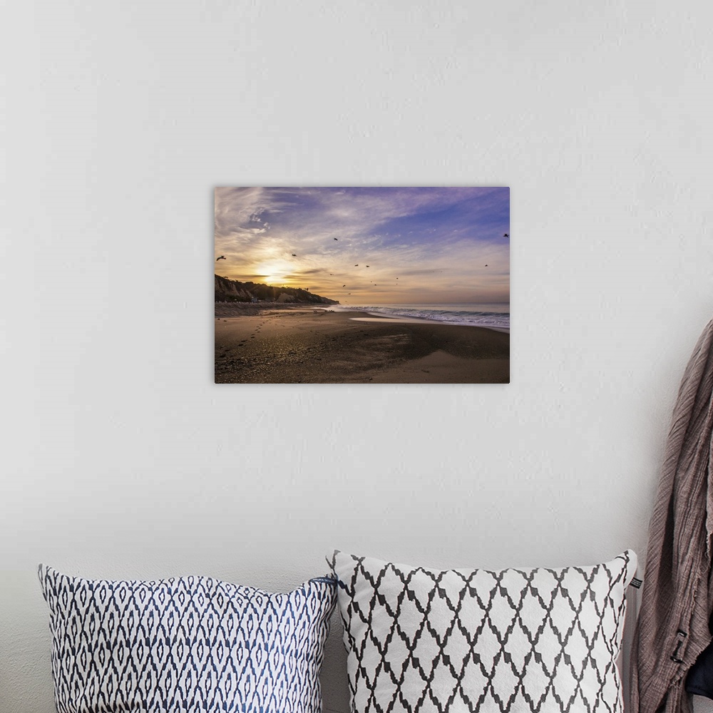 A bohemian room featuring View from a sandy beach of a sunrise in a cloudy sky.