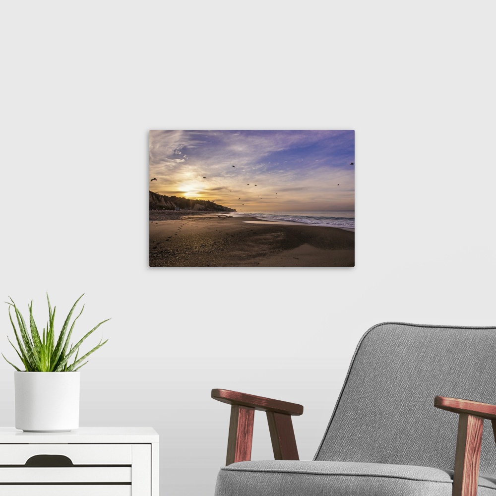 A modern room featuring View from a sandy beach of a sunrise in a cloudy sky.