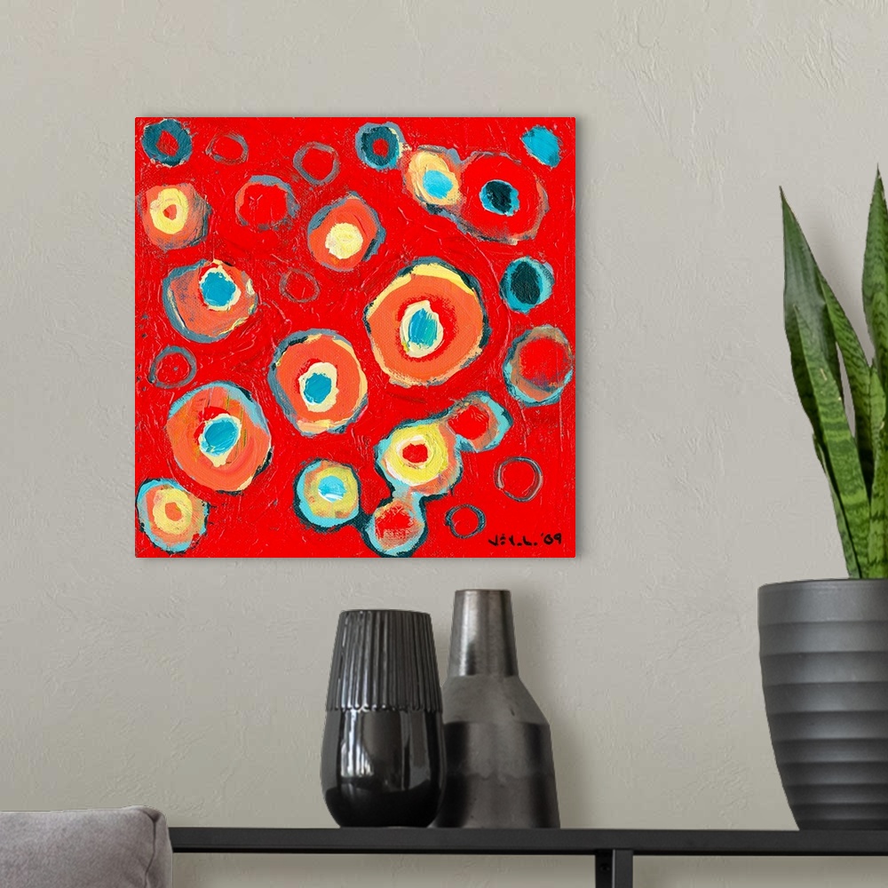 A modern room featuring Large abstract painting featuring various vibrantly-colored circular designs inside one another o...