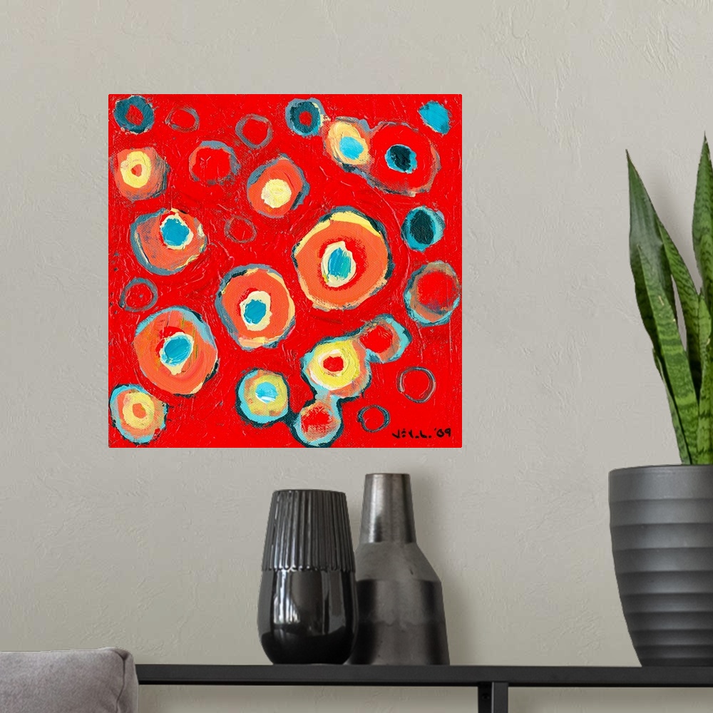 A modern room featuring Large abstract painting featuring various vibrantly-colored circular designs inside one another o...