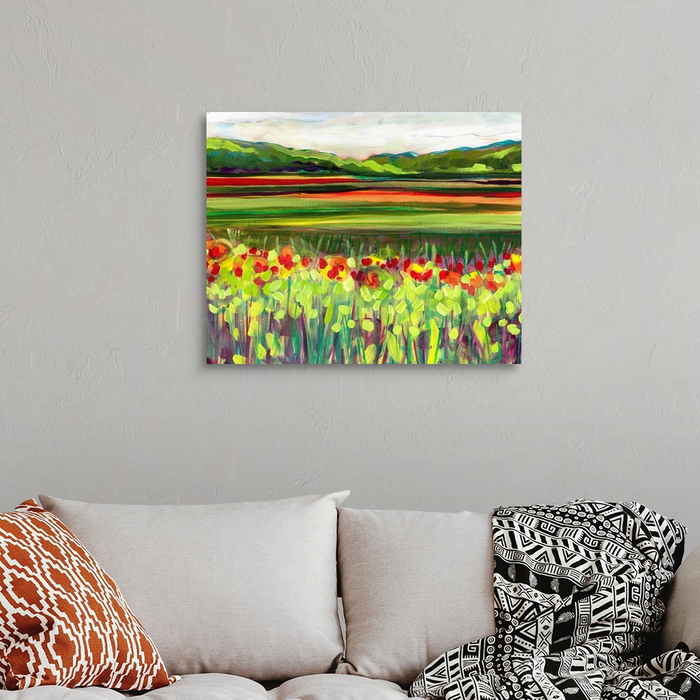 A bohemian room featuring Large, landscape fine art painting of a meadow of wildflowers in front of a green hillside on the...