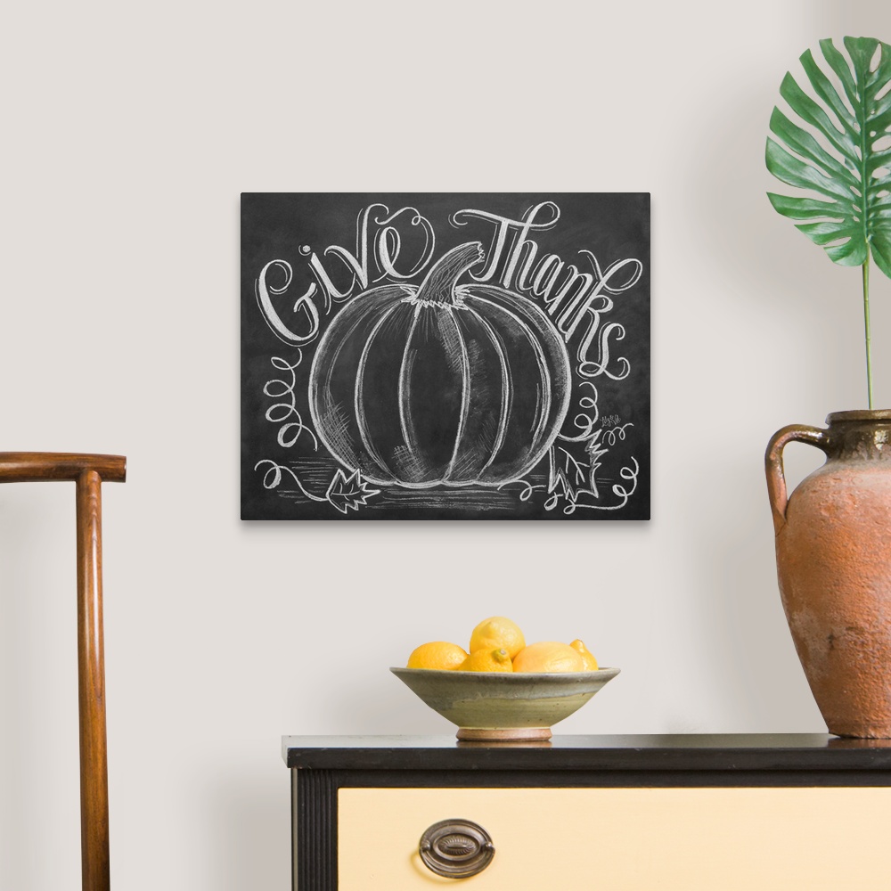 A traditional room featuring "Give Thanks" handwritten with a drawing of a large pumpkin in white chalk on a black background.