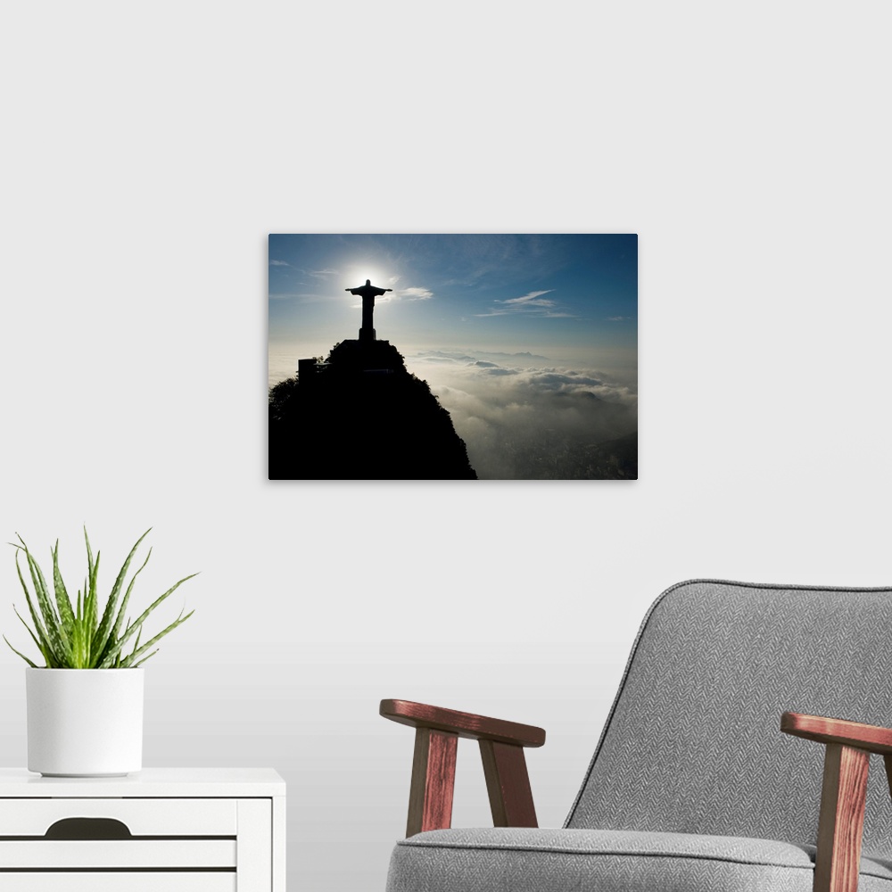 A modern room featuring Christ the Redeemer Statue at sunrise above the clouds.