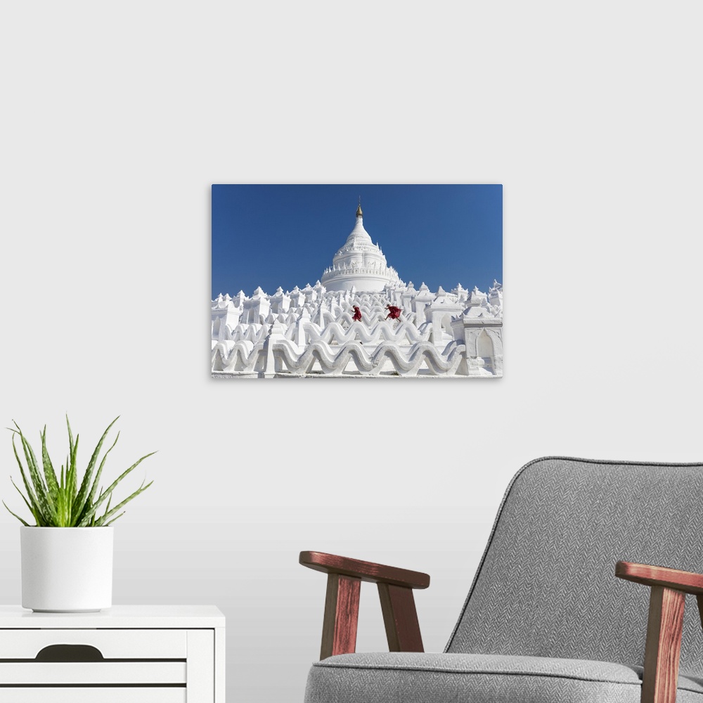 A modern room featuring Two young Buddhist monks run and jump across the white walls of Hsinbyume Pagoda, Mingun, Mandala...