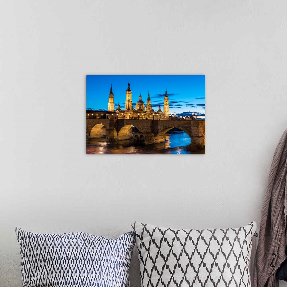 A bohemian room featuring Cathedral Of Our Lady Of The Pillar And Stone Bridge At Dusk. Zaragoza, Aragon, Spain