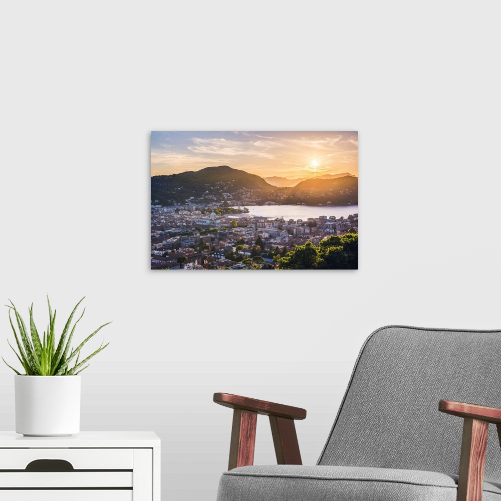A modern room featuring Como, Lombardy, Italy. High angle view over the city and the Como Cathedral at sunset.