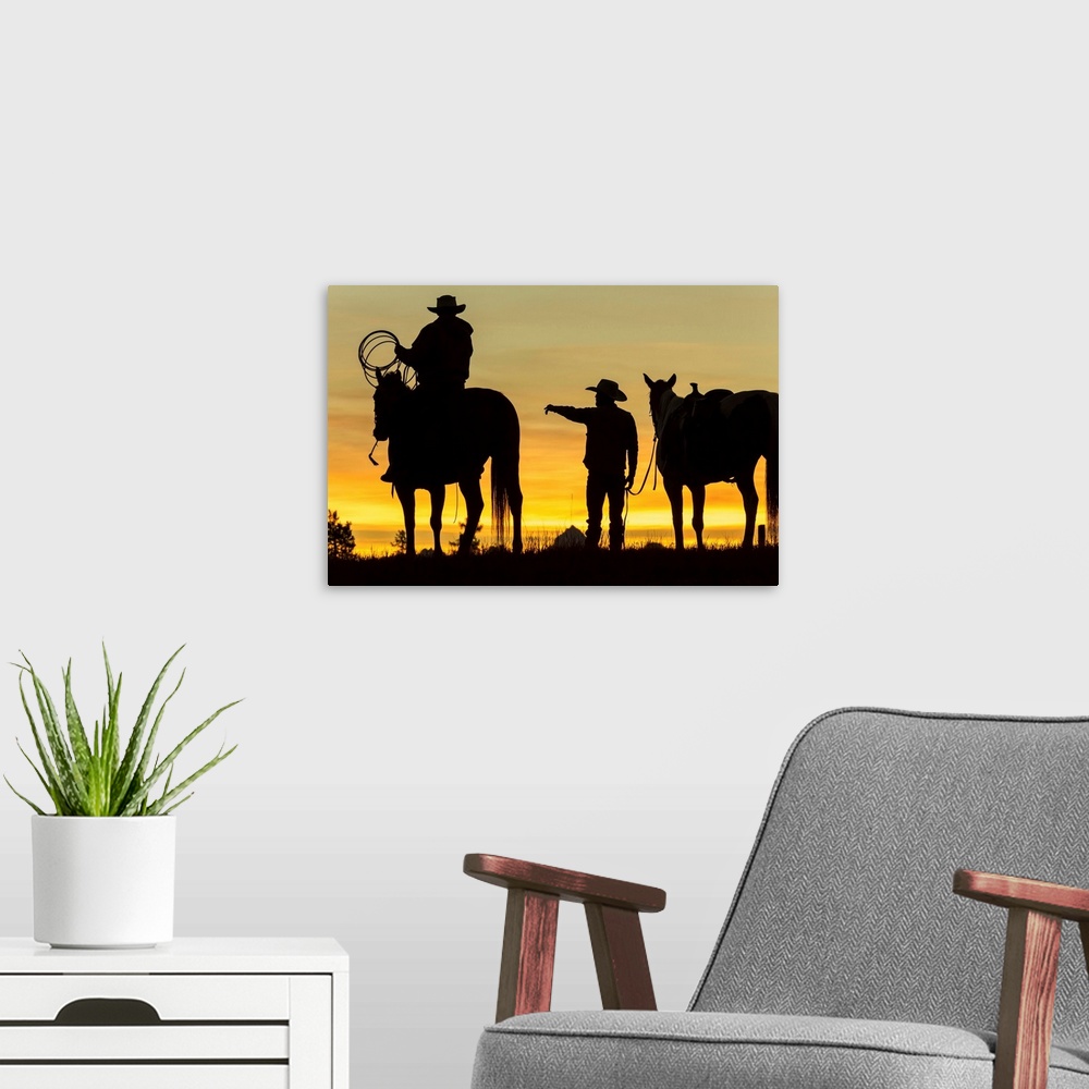 A modern room featuring Cowboys and horses in silhouette at dawn on ranch, British Colombia, Canada.