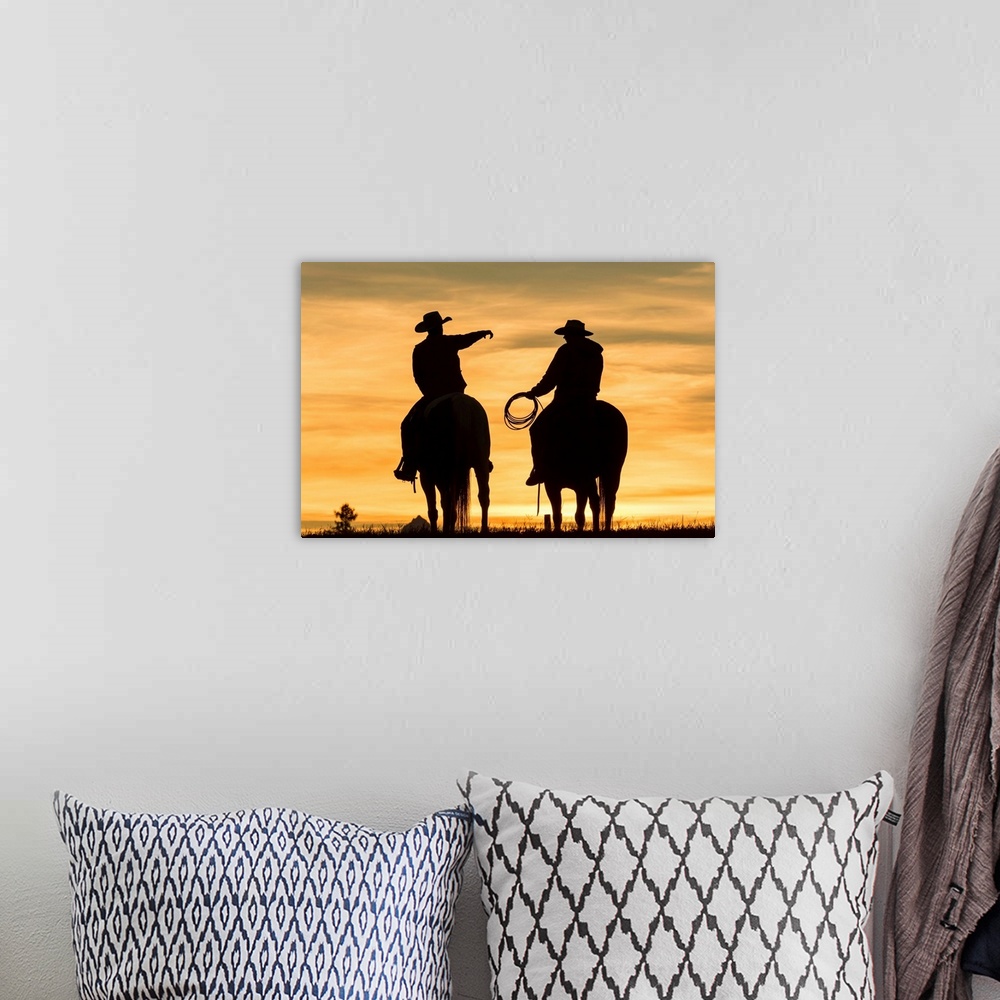 A bohemian room featuring Cowboys and horses in silhouette at dawn on ranch, British Colombia, Canada.