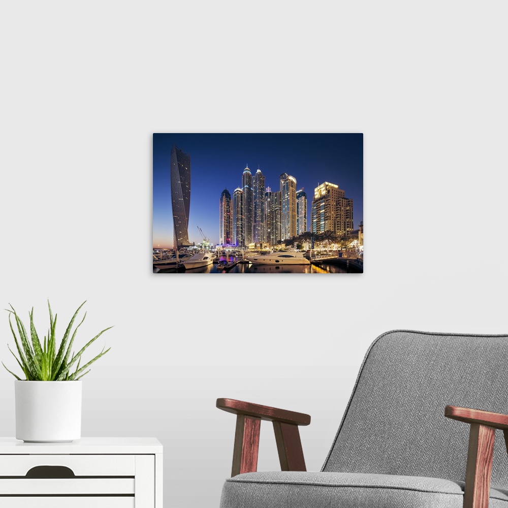 A modern room featuring Dubai Marina at twilight with the Cayan Tower (Infinity Tower), the Dubai Marriott Harbour Hotel ...