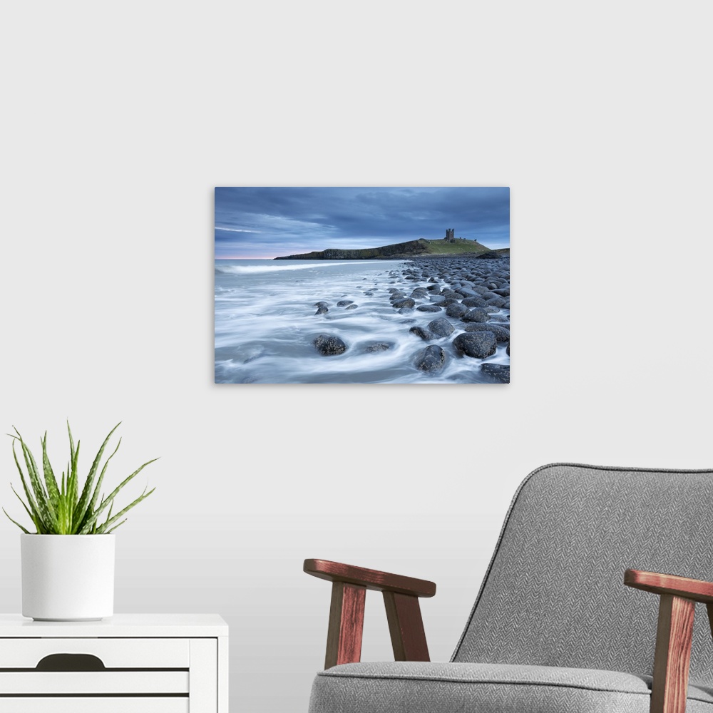 A modern room featuring The ruins of Dunstanburgh Castle overlooking the boulder strewn shores of Embleton Bay, Northumbe...