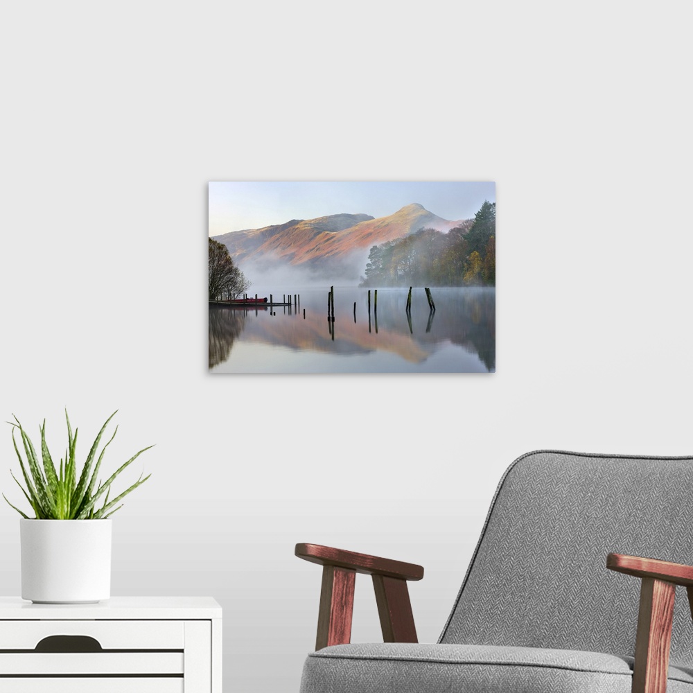 A modern room featuring Early morning tranquil scenes of Derwent Water, with Catbells rising out of the mist in the backg...