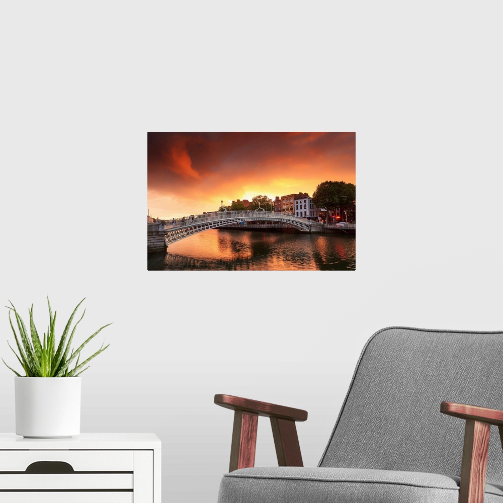 A modern room featuring Europe, Dublin, Ireland, people crossing Halfpenny bridge on the Liffey river at sunset