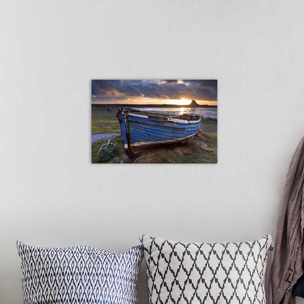 A bohemian room featuring Decaying fishing boat on Holy Island at dawn, with Lindisfarne Castle beyond, Northumberland, Eng...