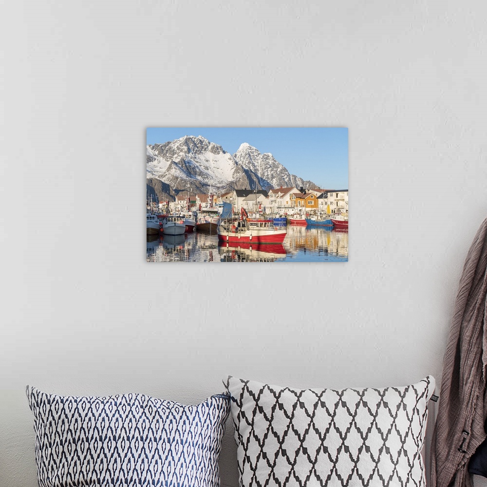 A bohemian room featuring Fishing boats in the harbour, with snowcapped mountains in the background. Henningsvaer, Nordland...