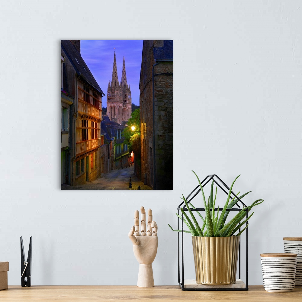A bohemian room featuring France, Brittany, Finistere, Quimper, view down cobbled street to Saint Corentin cathedral at dusk.