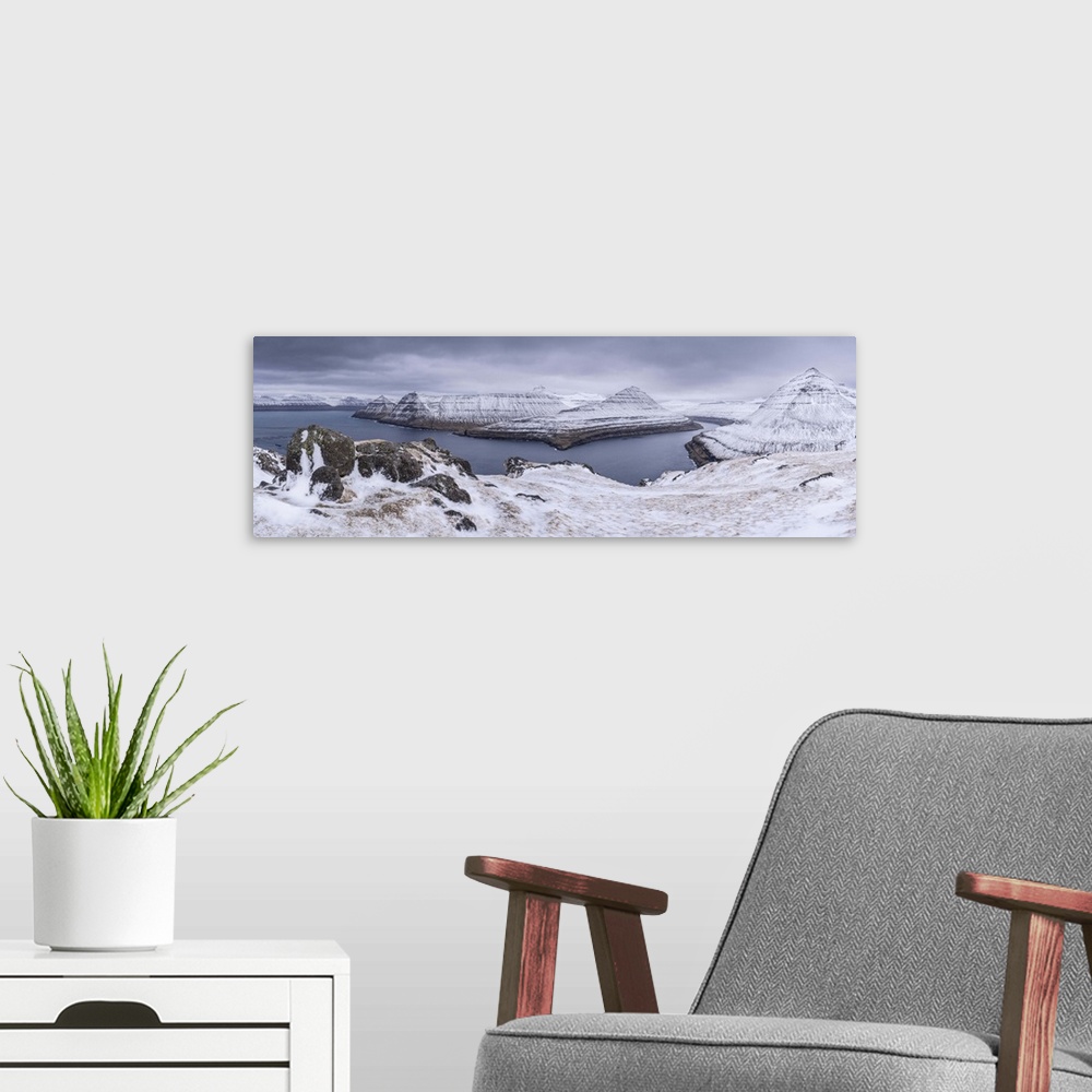 A modern room featuring Snow covered mountain scenery above Funningsfjordur on the island of Eysturoy, Faroe Islands, Den...